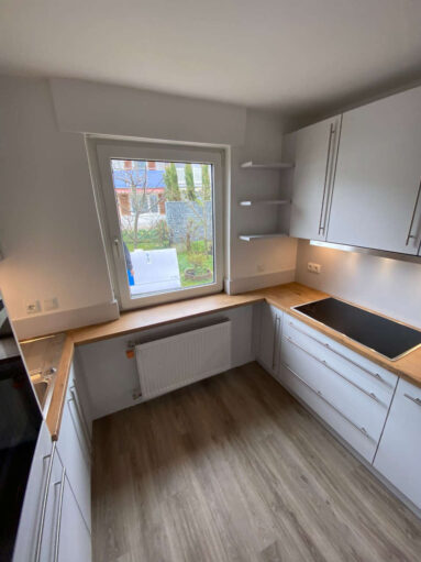 Küche in U-Form mit weißer Front und Arbeitsplatte aus Holz (z.B. Eiche)