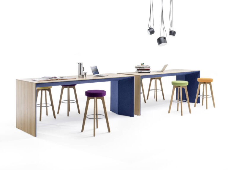 Zwei Stehtisch-Arbeitsplätze für Meetings mit bunten Hockern. Die Tische haben eine Holzoberfläche mit blauen Farbelementen.